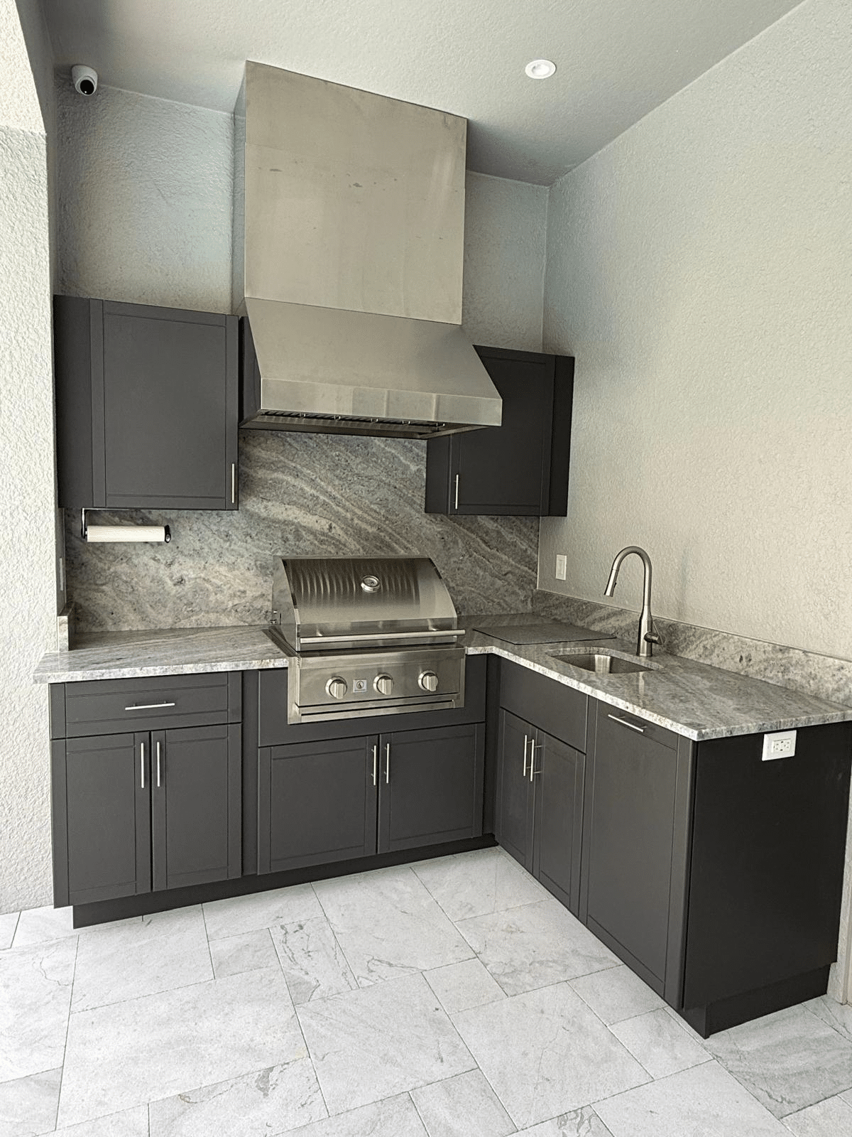 Installed charcoal HDPE polymer outdoor kitchen cabinets in an L-shape layout in Central Florida