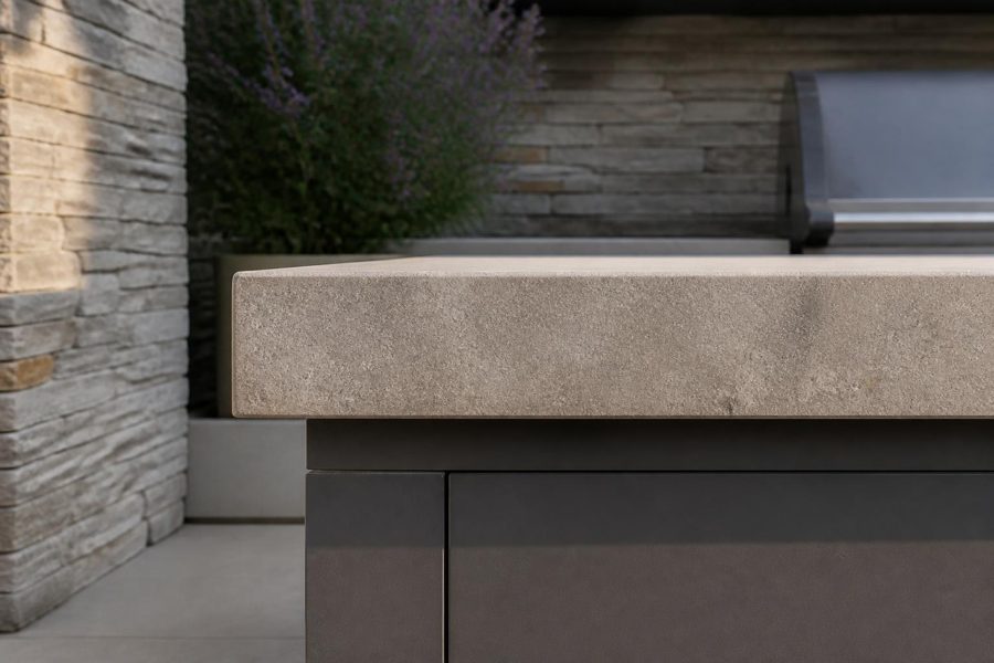 Close view along a stone countertop overhang above a marine-grade polymer grill cabinet